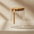 woodnestcraft glass storage jar with bamboo lid and wooden scoop on a beige textured background