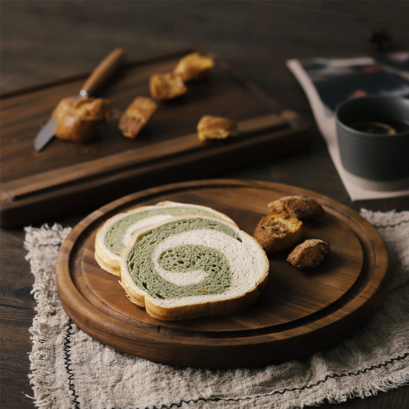 woodnestcraft round walnut wood serving board with sliced swirl bread on a rustic linen cloth