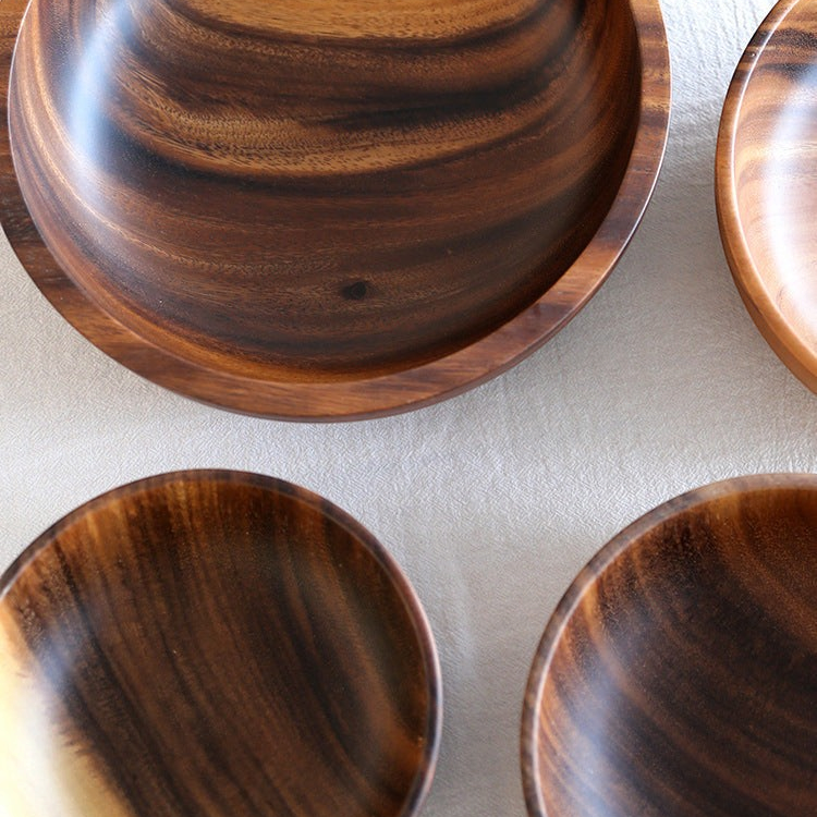 woodnestcraft set of three round solid wood serving bowls with a matching wooden spoon on a beige linen tablecloth