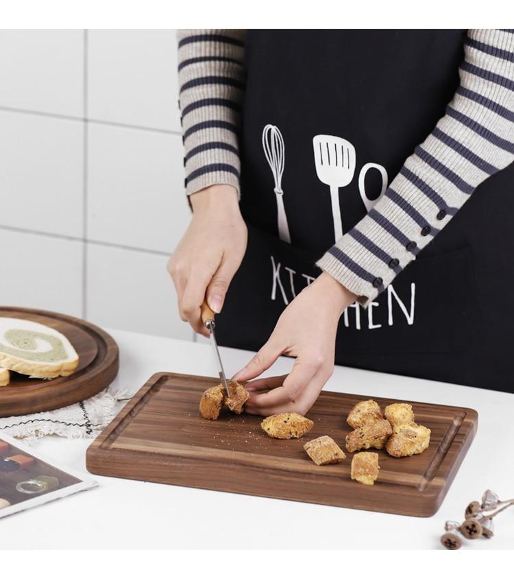 woodnestcraft rectangular solid walnut wood cutting board with juice groove being used to chop bread