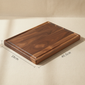 woodnestcraft rectangular solid black walnut wood cutting board with a juice groove on a neutral fabric background